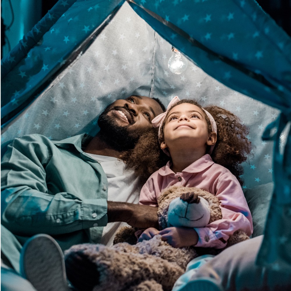 Family before going to bed mother reads to her child son book near a lamp in the evening